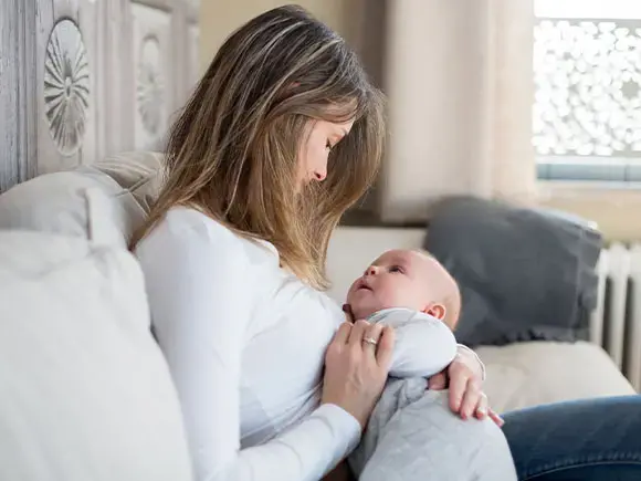 Una madre se prepara para amamantar a su bebé. 